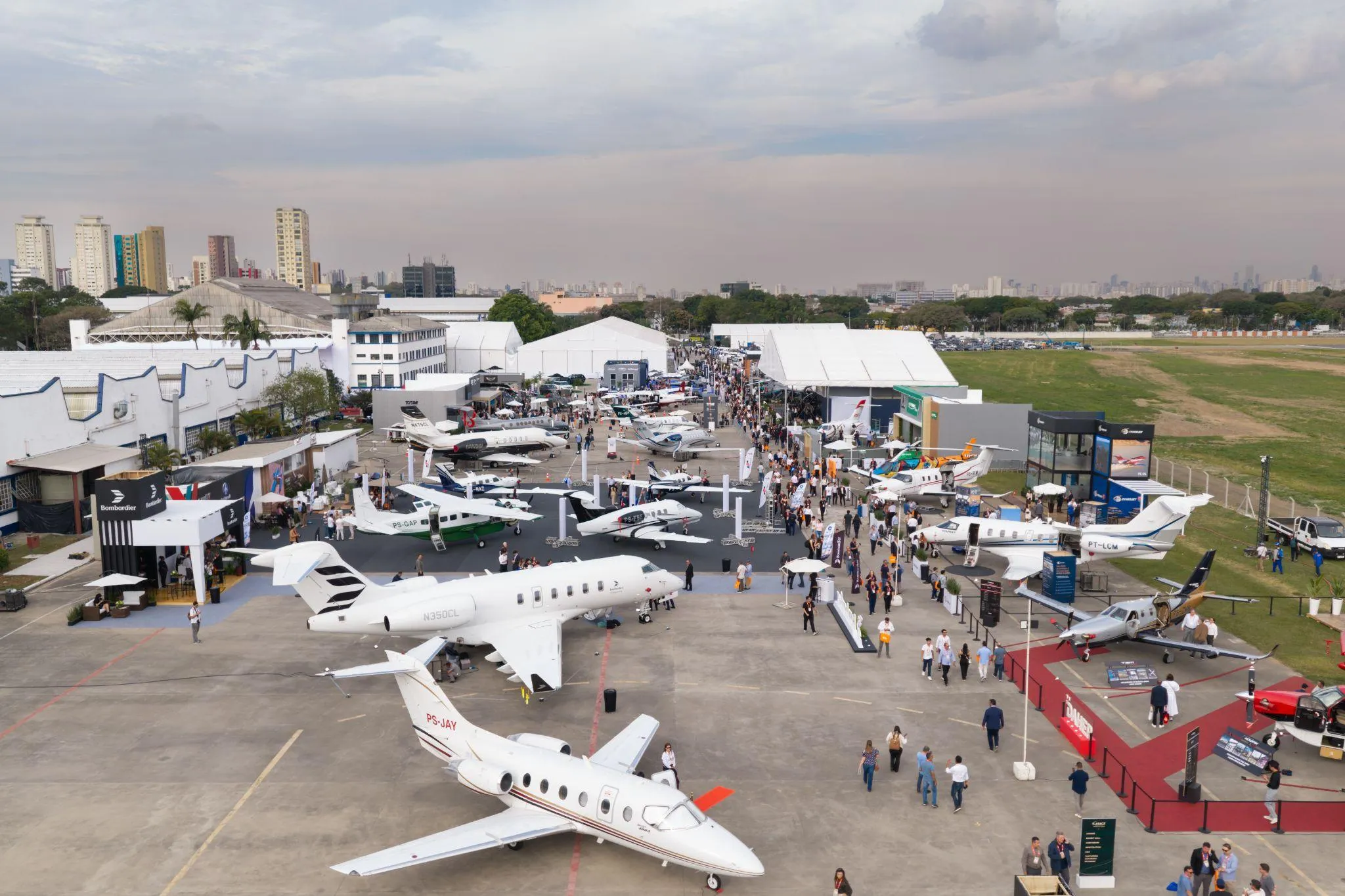 Vista aérea da exposição estática da LABACE, com dezenas de aeronaves e visitantes circulando pelo pátio